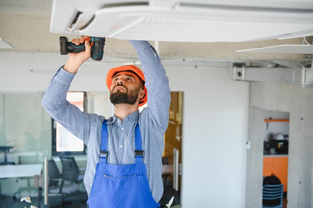 Technician working on a ceiling-mounted HVAC unit